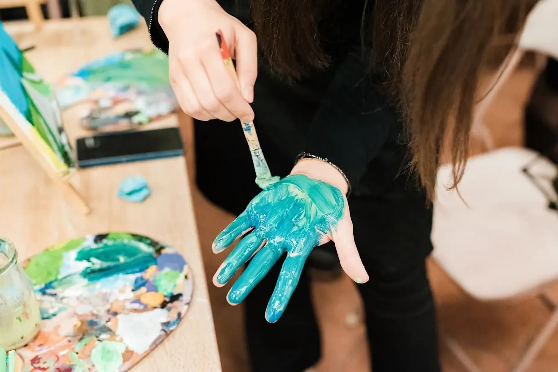 Paint-covered hand and palette at the workshop